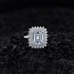 Elegant emerald cut sparkling diamond ring with double halo on textured black stone background