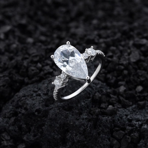 Pear cut simulated diamond sterling silver ring on black volcanic rock background