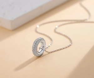 Macro detail of silver circle pendant with pave-set cubic zirconia on thin chain