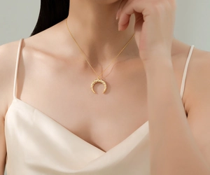 Gros plan d'un collier croissant de lune en or 14 carats porté par un mannequin
