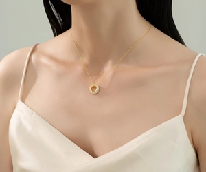 Close-up of a gold circular necklace with shimmering pavé stones worn by a model