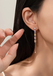 Close-up of a long tassel earring with four-color square stones on a female model