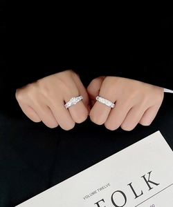 Detailed view of two S925 silver rings with pavé diamonds and a floral center stone