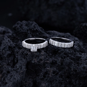 Macro shot of square-cut diamond ring and band set on a dark textured volcanic rock
