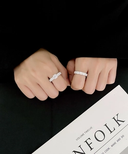 Close-up of emerald-cut silver ring and triple-row pavé band worn on a hand