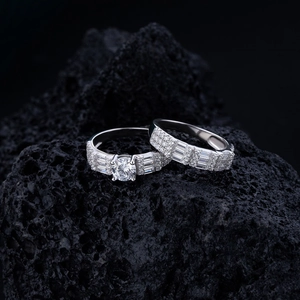 Macro shot of silver wedding ring set with square and round diamonds on black stone