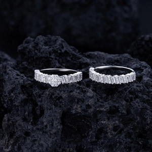 Macro shot of silver wedding rings with baguette cut diamonds on black volcanic stone