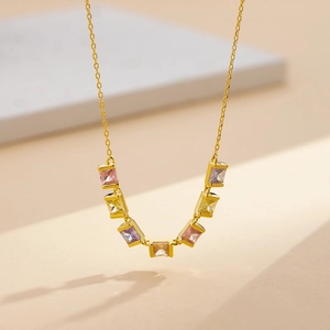 Elegant gold necklace with multi-colored square zircon pendant on a minimalist display