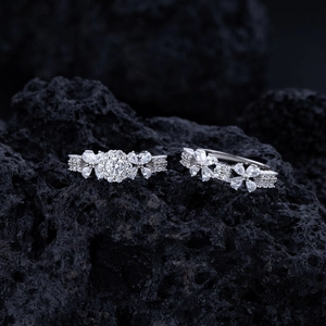 Detailed macro view of silver flower rings with cubic zirconia on black volcanic rock