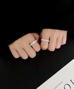 Detail of silver baguette-cut diamond rings worn together on a dark background
