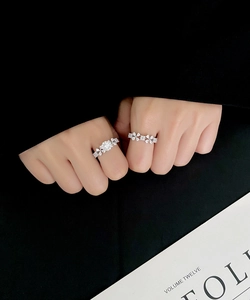 Close-up of S925 sterling silver rings with floral zircon pavé clusters on a finger