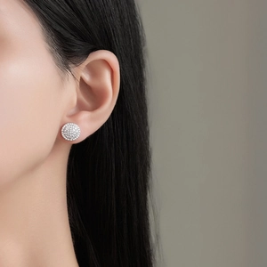 Close-up of pavé set round stud earrings with shimmering stones on a female model