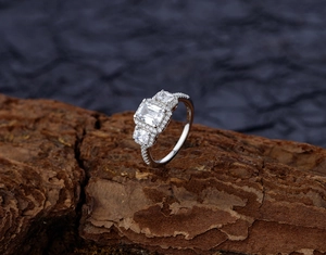 Macro detail of emerald-cut square crystal ring with pave diamonds on tree bark