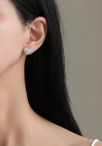 Close-up of double-layered heart stud earrings with sparkling cubic zirconia on model's ear