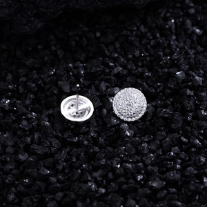 Macro shot of S925 sterling silver pave disk stud earrings on a dark textured rock