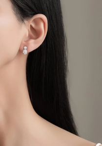 Close-up of model wearing oval pavé-set silver earrings with shimmering cubic zirconia