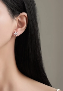 Gros plan d'un modèle portant un clou d'oreille flocon de neige en argent et zircon