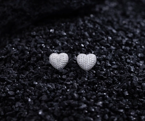 Macro shot of silver heart studs with pave-set sparkling zircons on a dark stone background