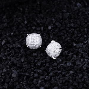 Macro shot of silver micro-pave square zircon stud earrings on dark mineral stones