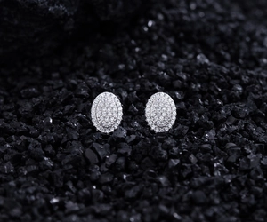 Close-up of silver S925 oval stud earrings with pavé zircon stones on black lava stones