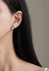 Detail of S-shaped silver earrings with cubic zirconia pavé on woman's earlobe