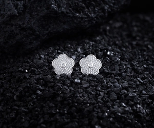 Vue macro de boucles d'oreilles camélia en argent avec diamants pavés sur pierre