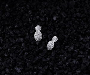 Macro detail of S925 silver oval earrings with pavé zircons on black volcanic rock