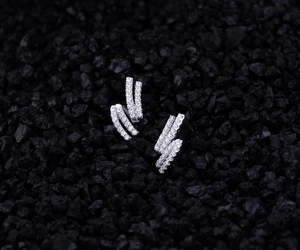Detailed view of S925 sterling silver curved earrings with sparkling cubic zirconia on black rock