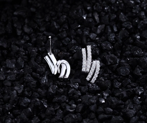 Detail of silver S925 earrings with double-layer streamline design and pave zircons