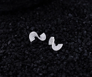 Detailed macro view of S-shaped silver stud earrings with sparkling cubic zirconia pavé
