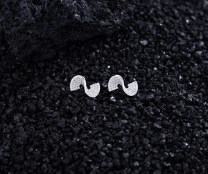 Macro view of S-shaped silver earrings inlaid with shimmering cubic zirconia stones