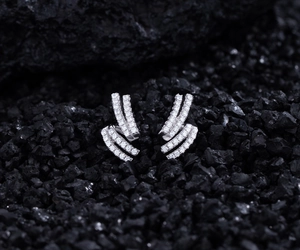 Macro shot of double-layer silver earrings with paved diamonds on black stones
