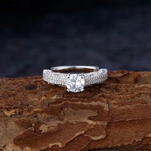 Classic round cut diamond ring with micro pavé setting on natural wood bark background