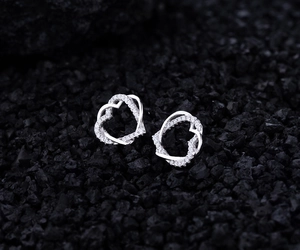 Dettaglio macro di orecchini a cuore in argento S925 con zirconi brillanti su sfondo scuro