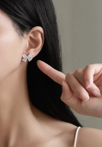 Close-up of sparkling bow knot stud earrings with micro-set diamonds on a model ear