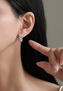 Close-up of S925 sterling silver pave-set chain hoop earrings on female model ear