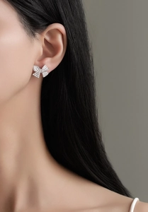 Detailed close-up of S925 sterling silver bow earrings with micro-paved diamonds on model