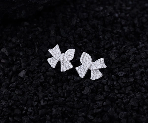 Macro shot of silver bow earrings with micro-pave white zircon on black mineral stones