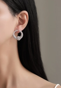 Close-up of S925 sterling silver hoop earrings with pavé zircons worn by a model