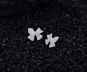 Macro detail of S925 silver bow earrings with micro-pave white zircon on black volcanic stone