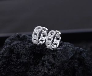 Macro shot of silver S925 curb chain hoop earrings with cubic zirconia on black rock
