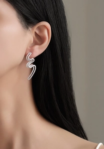 Gros plan de boucles d'oreilles S925 en vagues avec oxydes de zirconium sur mannequin
