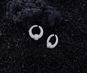 Macro detail of S925 silver U-shaped earrings with paved zircons on volcanic rock