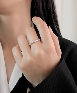 Gros plan d'une bague ondulée en argent sertie de micro-diamants portée sur le doigt