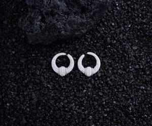 Macro detail of S925 silver U-shaped earrings with zircons on volcanic rock background