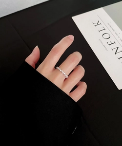 Gros plan d'une délicate bague en argent sertie de diamants ronds sur un doigt