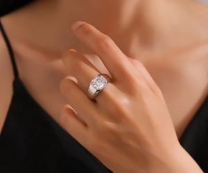 Macro shot of silver wide band ring featuring an emerald cut cubic zirconia on hand