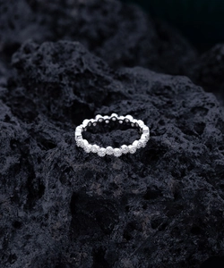 Gros plan sur bague éternité en argent avec micro-pavé de diamants sur roche volcanique