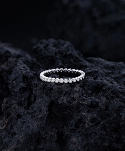 Macro shot of S925 silver wavy ring with inlaid cubic zirconia on black volcanic rock