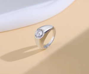 Close-up of a silver bezel set round cut sparkling gemstone on a wide band ring